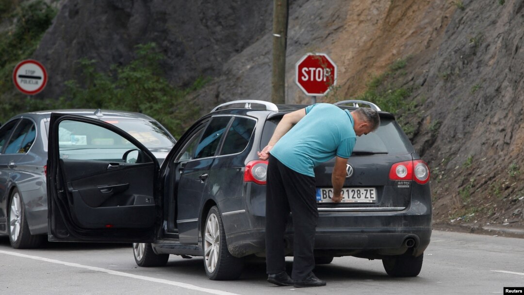 FILE - A driver removes a sticker covering the national markings on his car plates at the Jarinje border crossing, Kosovo, Sept. 1, 2022. 
