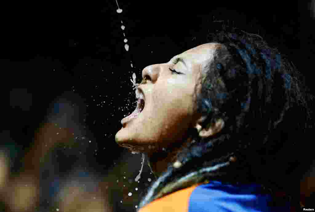 A woman drinks homemade alcohol poured from the mouth of an idol of "Swet Bhairab" during the annual Indra Jatra festival to worship Indra, Kumari and other deities and to mark the end of monsoon season in Kathmandu, Nepal, Sept. 11, 2022.