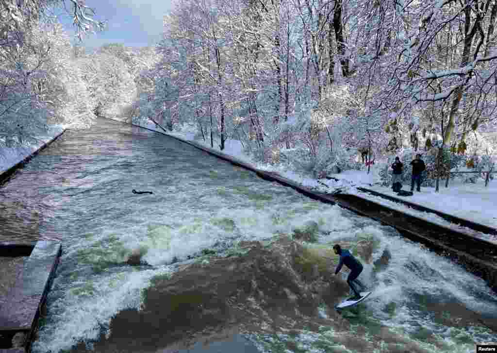 A man surfs the waves on the Eisbach river, one day after heavy snowfall hit Bavaria and its capital Munich, Germany, Dec. 3, 2023.