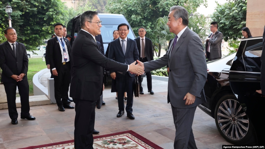 In this photo released by Agence Kampuchea Press (AKP), Chinese Foreign Minister Wang Yi, front right, greets Cambodia's Foreign Minister, SOK Chenda Sophea, front left, in Phnom Penh, April 21, 2024. 