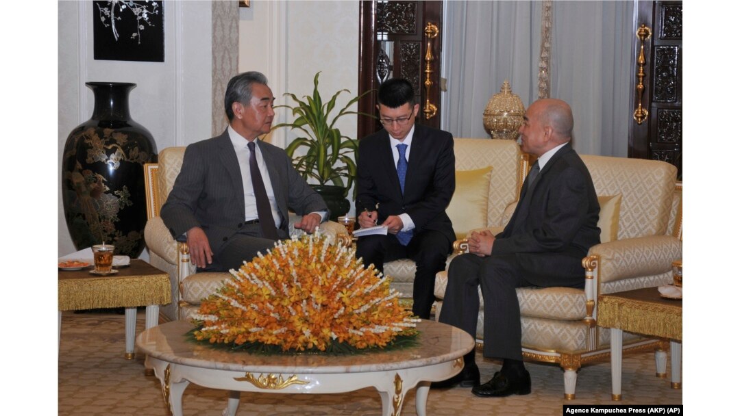 In this photo released by Agence Kampuchea Press (AKP), Chinese Foreign Minister Wang Yi, left, is welcome meeting by Cambodia's King Norodom Sihamoni, right, in Royal Palace, in Phnom Penh, April 21, 2024.