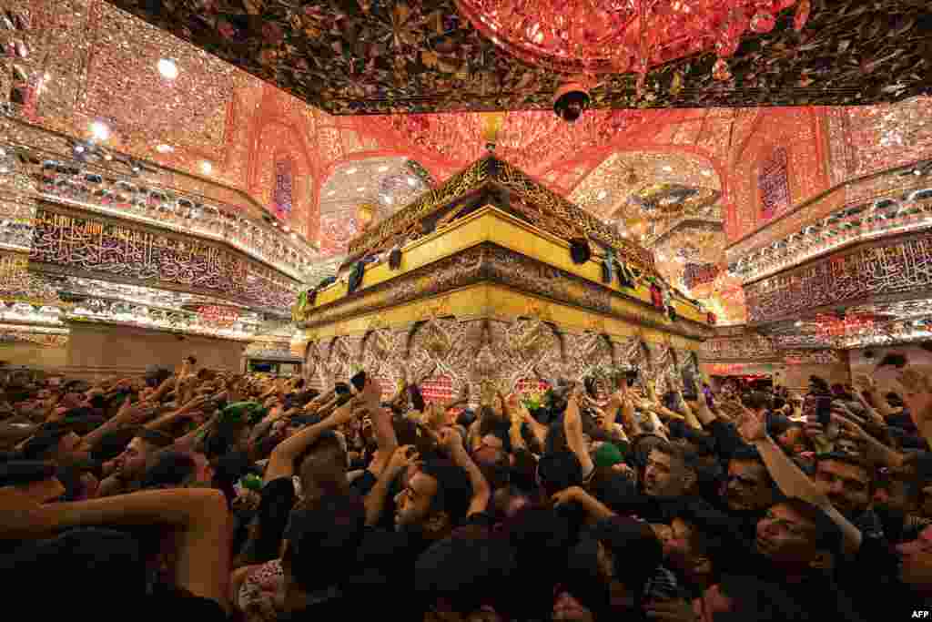 Shiite Muslim devotees reach to receive a blessing from the tomb of Imam Hussein, the Prophet Mohammed's grandson, at the Imam's shrine in Iraq's central holy city of Karbala, during the Arbaeen religious festival.