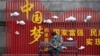 资料照：一名戴着口罩的男子在武汉街头一个中国梦的政府宣传牌下打盹。（2020年4月8日）