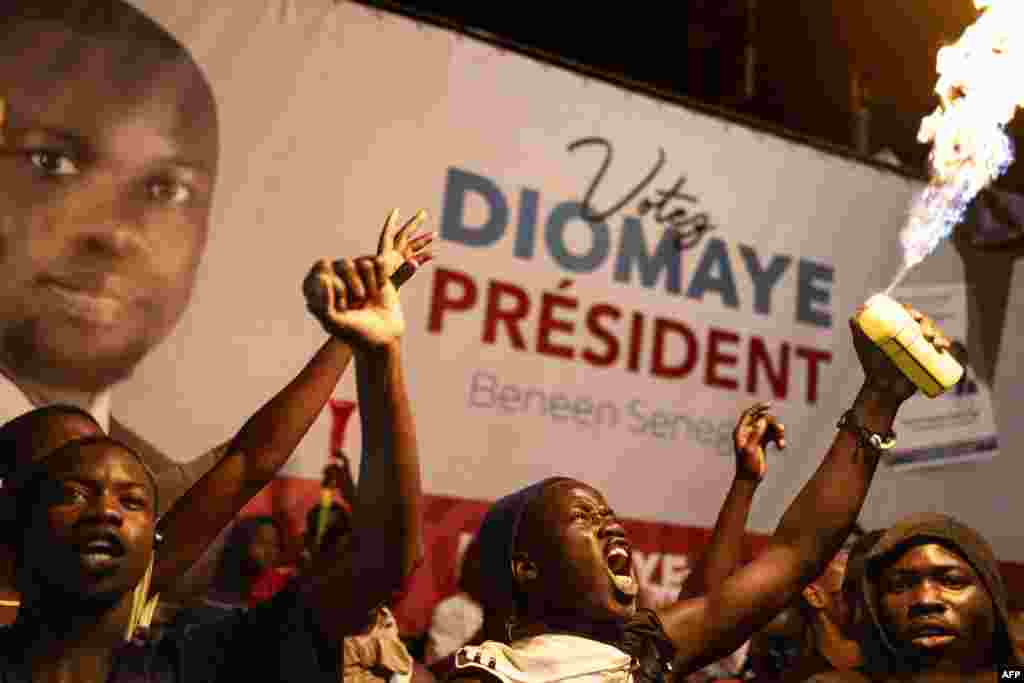 Apoiantes do candidato presidencial da oposição Bassirou Diomaye Faye e do líder da oposição Ousmane Sonko festejam na sede da coligação de Diomaye durante a contagem dos votos, em Liberte 4, Dakar, a 24 de março de 2024. 
