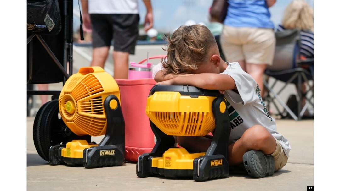 FILE - Braxton Hicks, 7, of Livingston, Texas, holds his face to a portable fan to cool off during a baseball tournament in Ruston, La., Aug. 9, 2023. (AP Photo/Gerald Herbert)