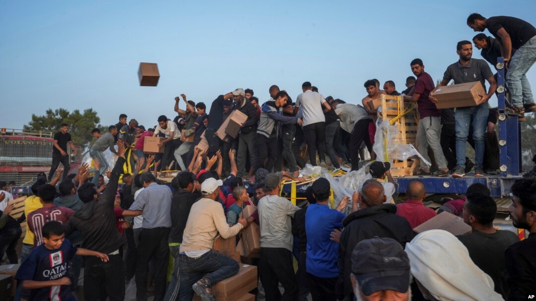 Palestinians storm trucks loaded with humanitarian aid brought in through a new U.S.-built pier in the central Gaza Strip, May 18, 2024.
