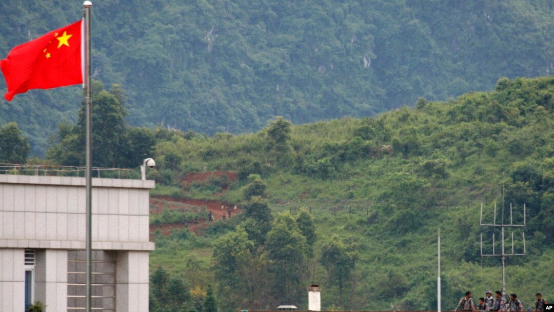 FILE - Myanmar government troops stand on a rooftop on the Myanmar side, near a Chinese flag from the Chinese border town of Nansan in southwestern China's Yunnan province, Aug 30, 2009. 