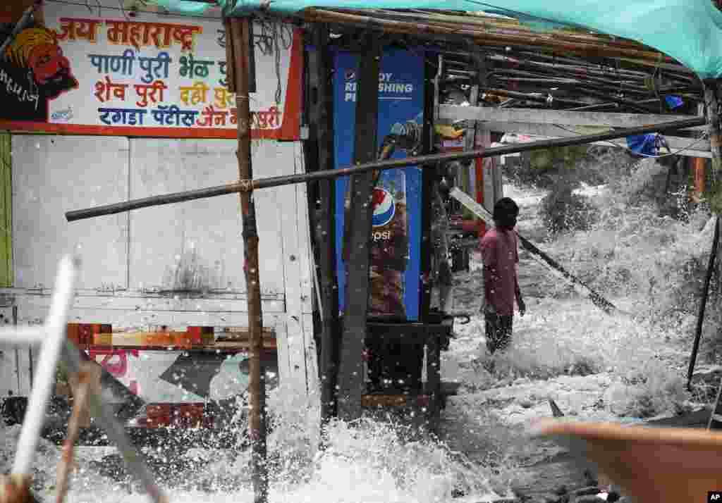 A man stands as sea water enters a food stall on the Arabian Sea coast during high tide in Mumbai, India.