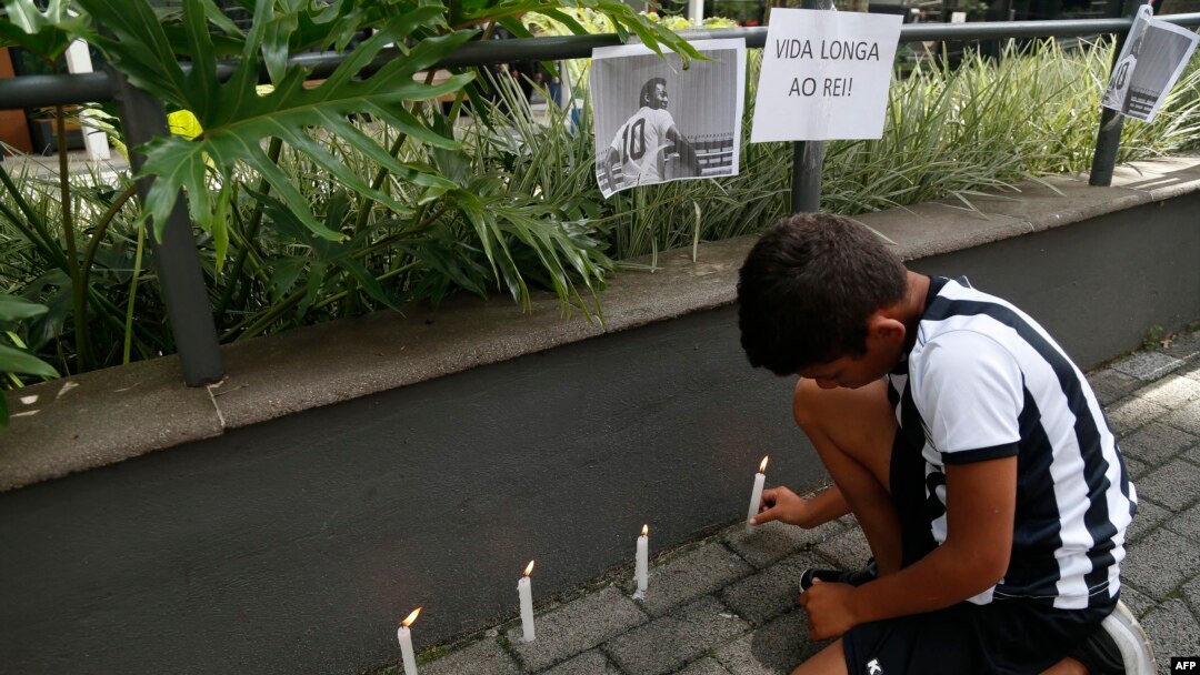 A child fan of Santos lights a candle next to a picture of Brazilian football legend Pele during a vigil outside the Albert Einstein Israelite Hospital entrance, where the former player is hospitalized in Sao Paulo, Brazil, on Dec. 4, 2022.
