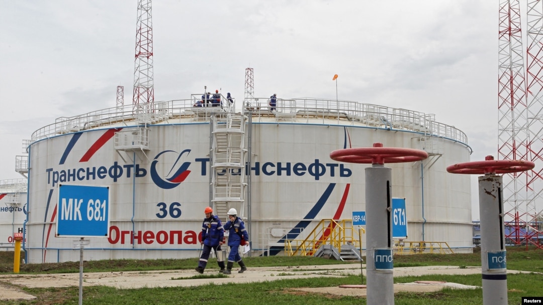 FILE - Workers walk past a storage tank at the Kaleikino oil pumping station of Transneft Kama Region, near Almetyevsk, Russia, April 27, 2022.