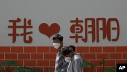 北京朝陽區兩個帶著口罩的居民去排隊做新冠核酸檢測。 （2022年5月11日）