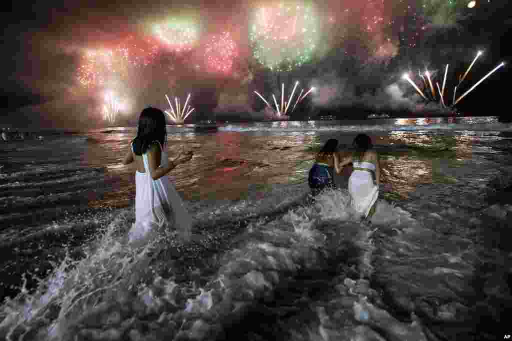 People bring in the New Year as they watch fireworks explode over Copacabana Beach in Rio de Janeiro, Brazil, Jan. 1, 2023.