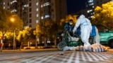 2022年4月11日，身穿防护服的送货员在中国上海的一个住宅小区门口提送食品。
