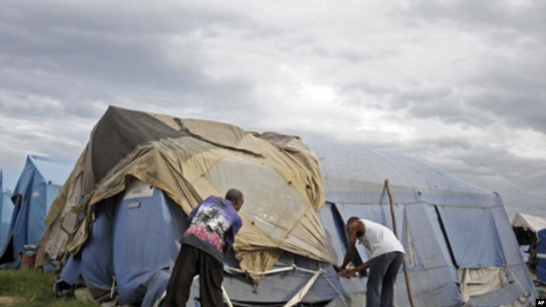 Men try to tie down their tent, which serves as their home, as Tropical Storm Emily idles just south of the slum area of Cite Soleil, Haiti, August 4, 2011