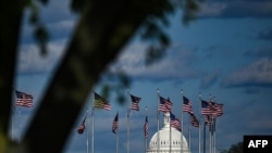 FILE - The dome of the US Capitol building is seen behind a row of US flags on April 10, 2020, in Washington, DC.