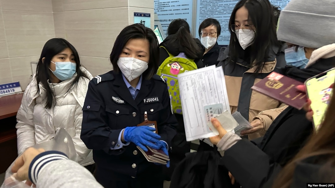An officer collects passports from residents for renewal and re-applications at a community police station in Beijing, Wednesday, Dec. 28, 2022. (AP Photo/Ng Han Guan)