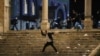 A Palestinian hurls stones at Israeli police during clashes at the compound that houses Al-Aqsa Mosque amid tension over the possible eviction of several Palestinian families, May 7, 2021.