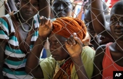 FILE - Women stand outside a U.N. Refugee Agency (UNHCR) site distributing soap, blankets and other items in Yei, in southern South Sudan, Nov. 14, 2016.