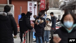 2021年1月14日人们在北京一家医院排队测试新冠病毒时通过手机刷健康码。（法新社提供）