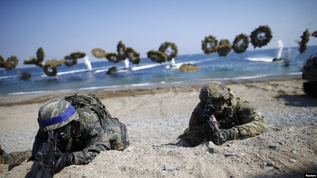 South Korean (blue headbands) and U.S. Marines take positions as amphibious assault vehicles of the South Korean Marine Corps fire smoke bombs during a U.S.-South Korea joint landing operation drill in Pohang, South Korea, March 12, 2016. 