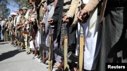 FILE - Houthi backers hold weapons during a protest outside the U.S. Embassy in Sanaa, Yemen, Jan. 18, 2021. 