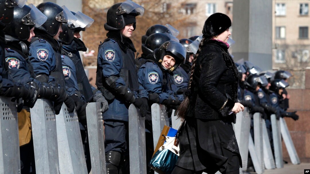 A woman walks past as Ukrainian riot police stand at the entrance of the regional administrative building in Donetsk, Ukraine, March 7, 2014.