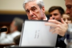FILE - Former special counsel Robert Mueller checks pages in the report as he testifies before the House Judiciary Committee hearing on Russian election interference, on Capitol Hill, July 24, 2019.