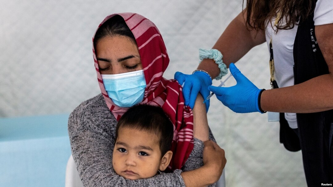 FILE - A migrant holds her baby as she receives a shot of the Johnson & Johnson vaccine against the coronavirus disease (COVID-19) in the Mavrovouni camp for refugees and migrants on the island of Lesbos, Greece, June 3, 2021.