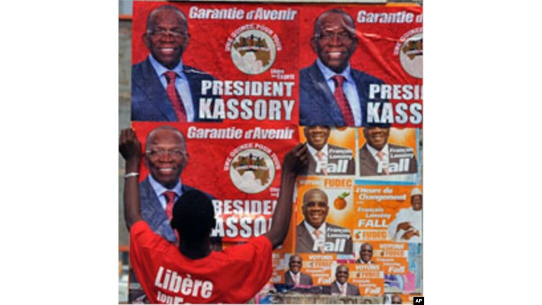 A man puts up electoral posters on a wall in a street of Conakry ahead of Guinea's first free election since independence in 1958., 24 Jun 2010