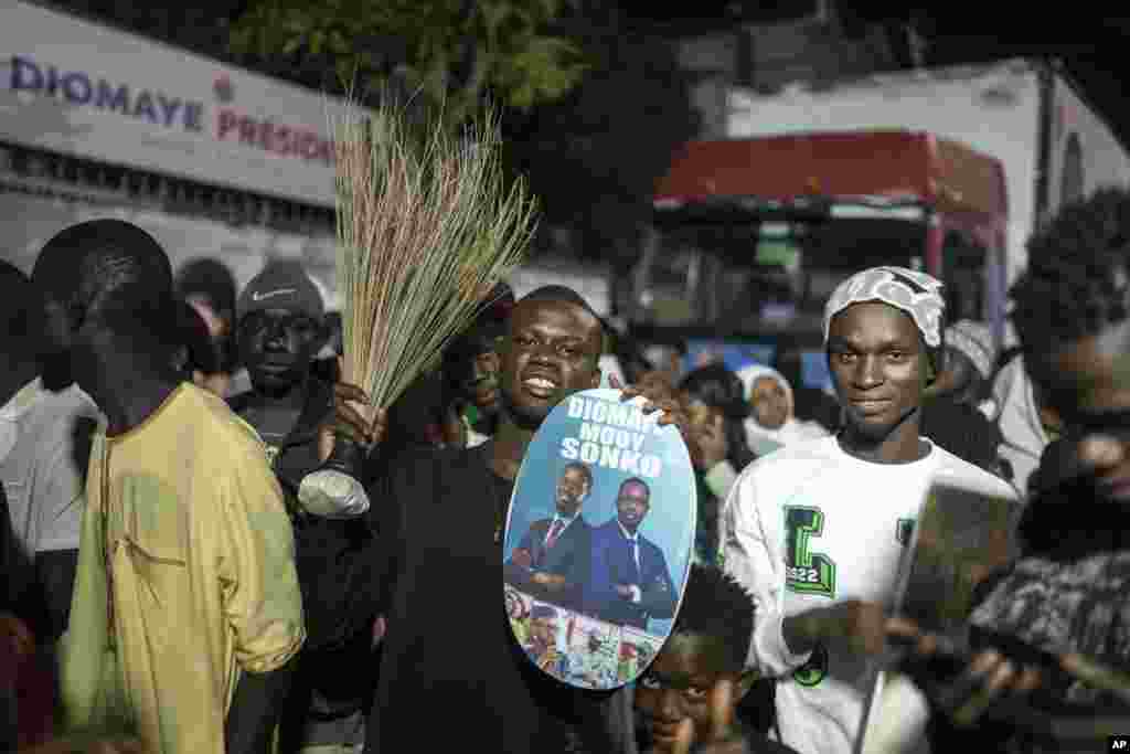 Apoiantes do candidato presidencial Bassirou Diomaye Faye e do principal líder da oposição senegalesa, Ousmane Sonko, reúnem-se à porta das suas sedes de campanha enquanto aguardam os resultados das eleições presidenciais, em Dakar, Senegal, domingo, 24 de março de 2024. 