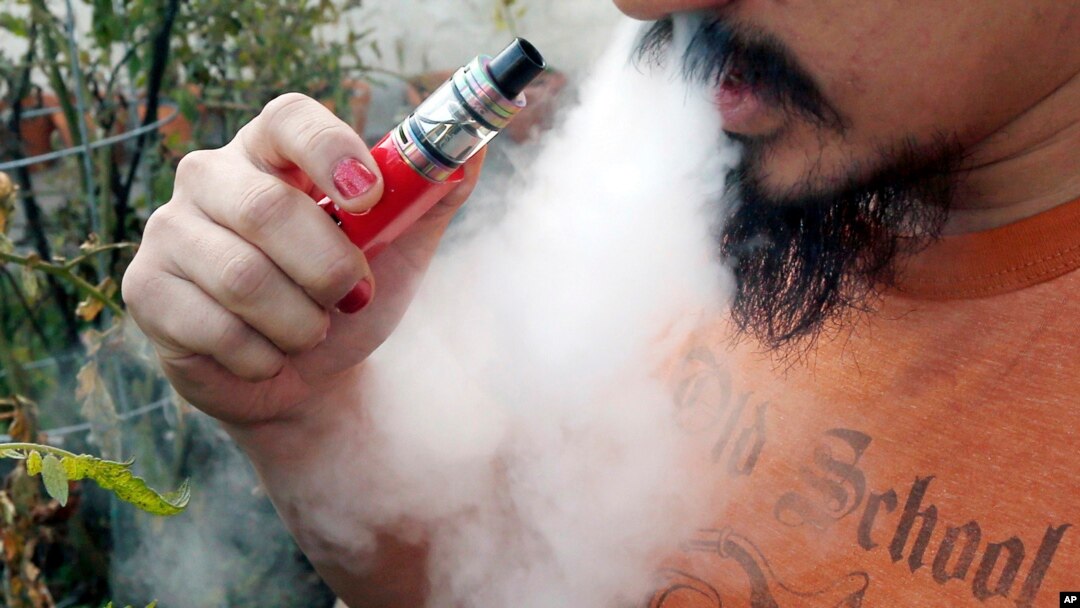 FILE - A man blows a puff of smoke as he vapes with an electronic cigarette, Oct. 18, 2019. 