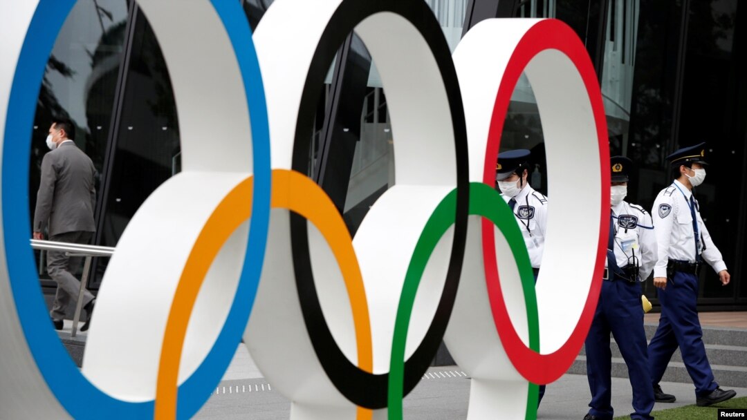 Security personnel stand guard near the Olympic rings monument during a rally by anti-Olympics protesters outside the Japanese Olympic Committee headquarters in Tokyo, Japan, May 18, 2021. 