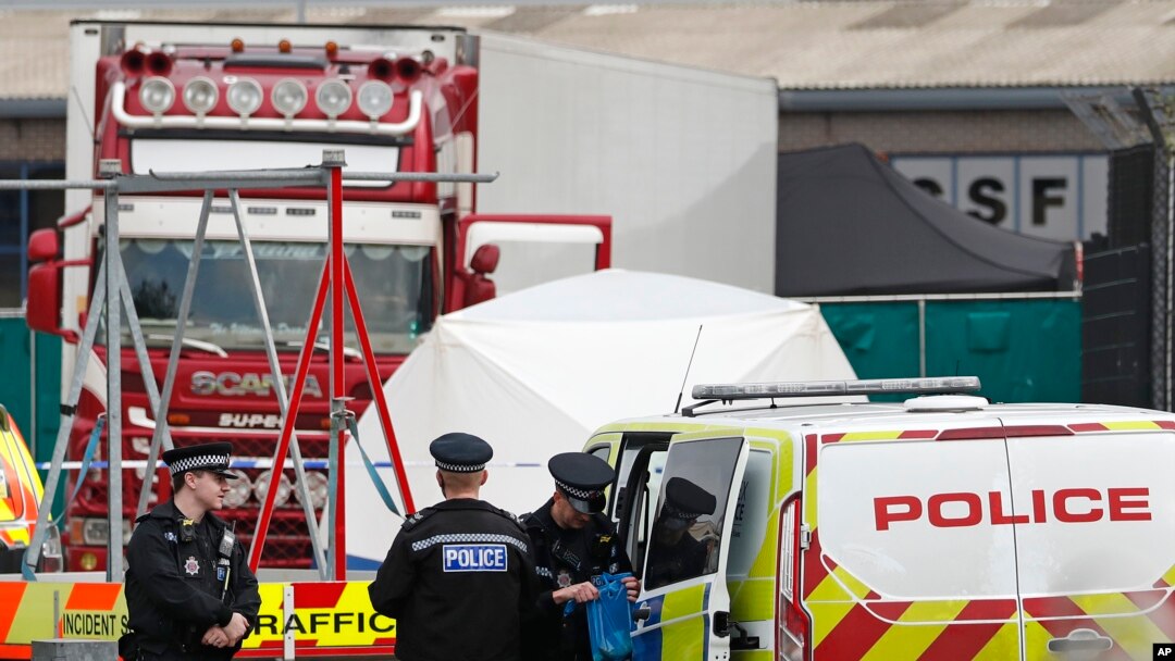 Police officers are on the scene after a truck, in rear, was found to contain a 39 dead bodies, later found to be Chinese nationals, in Thurrock, England, Oct. 23, 2019. 