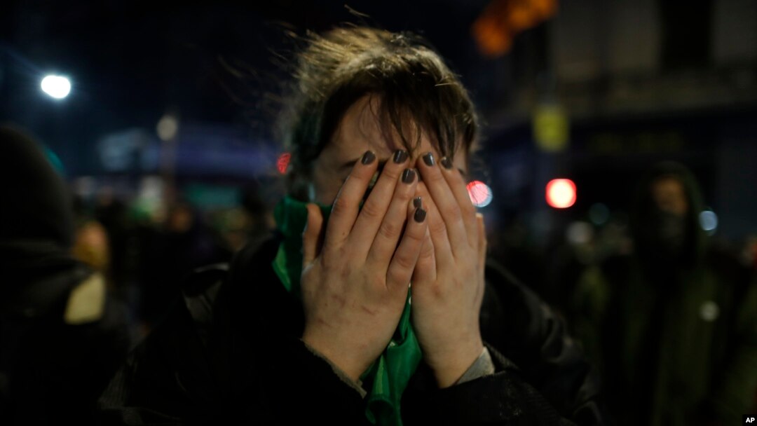 A pro-choice activist holds her face after lawmakers voted against a bill that would have legalized elective abortion in the first 14 weeks of pregnancy, outside Congress in Buenos Aires, Argentina, early Aug. 9, 2018. Argentina allows the procedure only in cases of rape or risks to a woman's health. 