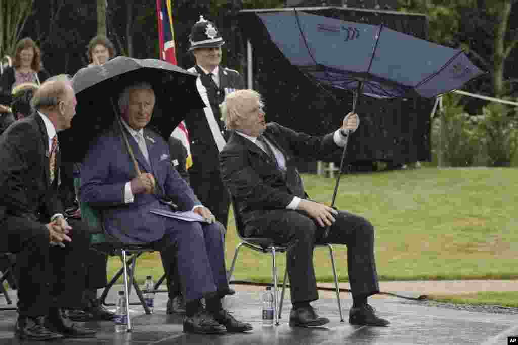 Britain's Prince Charles, center, and Prime Minister Boris Johnson, right, shelter from rain during the unveiling of the UK Police Memorial at the National Memorial Arboretum at Alrewas, England.
