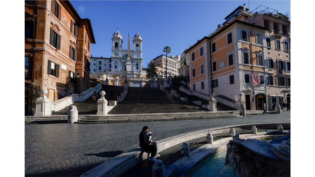 A person sits next to the Barcaccia fountain with Spanish steps in the background, as Italy goes back to lockdown as part of efforts put in place to curb the spread of the coronavirus disease (COVID-19), in Rome, Dec. 31, 2020.