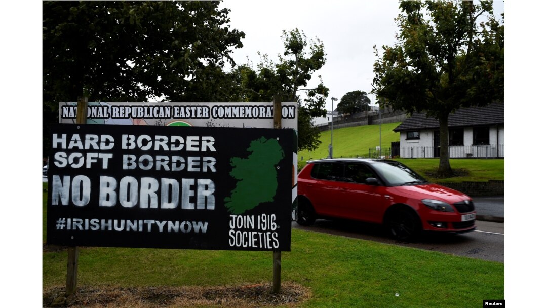 FILE - A car drives past a sign saying "No Border, Hard border, soft border, no border" in Londonderry, Northern Ireland, Aug. 16, 2017.