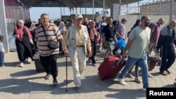 Palestinians with dual citizenship walk at the Rafah border crossing with Egypt, in the hope of getting permission to leave Gaza