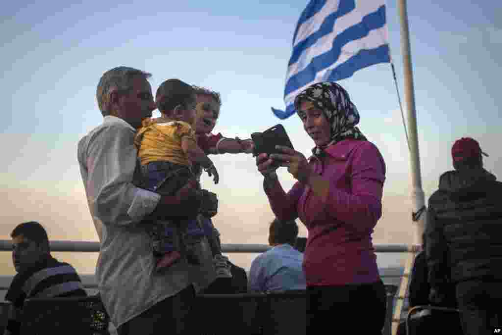 Refugees check their mobiles aboard a ferry traveling from the northeastern Greek island of Lesbos to the Athens' port of Piraeus, Sept. 10, 2015. (AP)