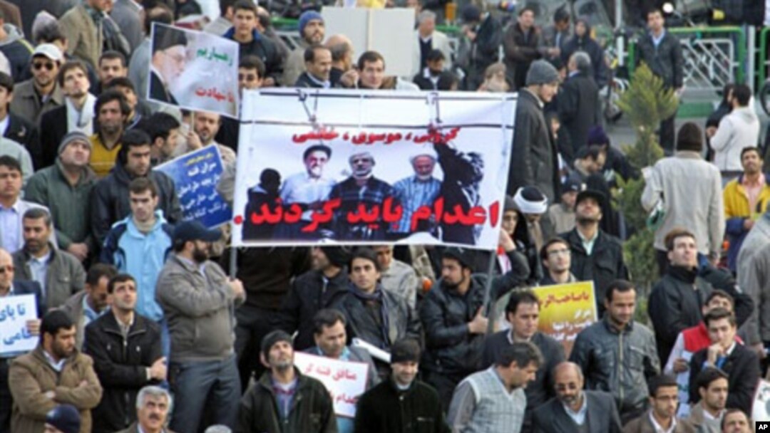 Iranian regime loyalists hold a poster with doctored pictures of former president Mohammad Khatami (L) and opposition leaders Mir Hossein Mousavi (C) and Mehdi Karroubi on the gallows during a pro-government demonstration in Tehran, February 18, 2011