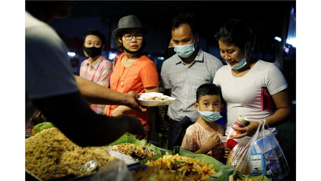 FILE - A family wearing protective masks purchases food at a market in Yangon, Myanmar, Feb. 3, 2020.