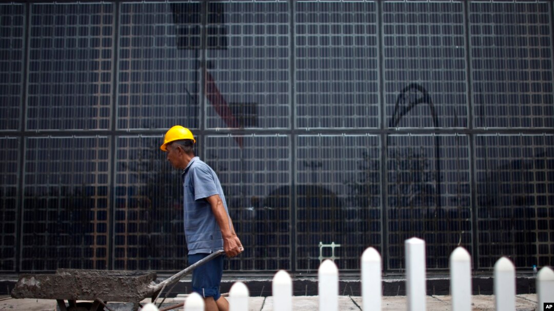 File - Solar panels at a factory in Baoding, in northern China's Hebei province. China, the world's largest polluter of climate changing emissions, is aggressively adopting solar energy to cut its dependence on fossil fuels.
