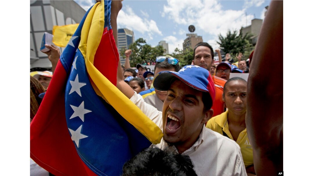 An opposition member waves a Venezuelan flag as National Assembly President Julio Borges speaks during a special public session at a square in Caracas, Venezuela, April 1, 2017.