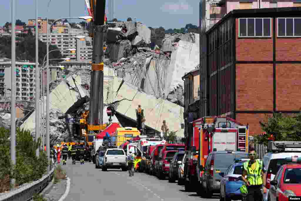 Firefighters and rescue workers stand at the site of a collapsed Morandi highway bridge in the port city of Genoa, Italy. Rescuers searched for survivors among towering slabs of concrete wreckage after the bridge collapse killed 39 people and sparked a furious government reaction against the viaduct’s operator.