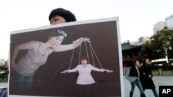 一名韩国大学生手举宣传画，展示韩国总统朴槿惠受其密友崔顺实控制