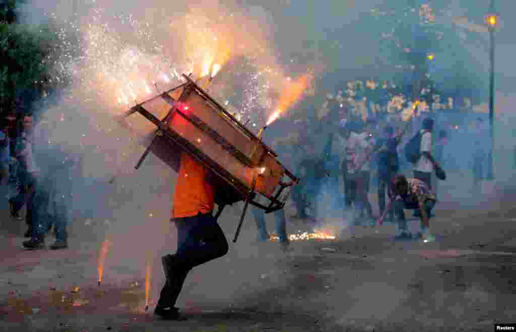 A man runs with a "toro encuetado", a structure resembling a bull and emitting exploding firecrackers, during celebration in honor of the Virgin Mary in Leon, Nicaragua, Aug.14, 2018.