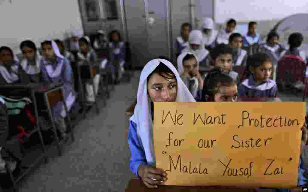 Pakistani girls display a poster while sitting at their desk, as their teacher, not shown, talks to them about Malala Yousafzai, Islamabad, Pakistan, October 12, 2012.