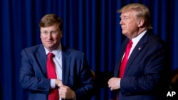 President Donald Trump welcomes Mississippi Lt. Gov. Tate Reeves, left, to the stage at a rally at BancorpSouth Arena in Tupelo, Miss., Nov. 1, 2019.