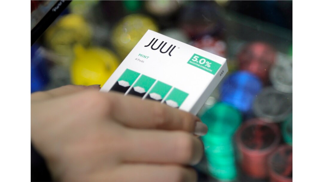 FILE - A woman buys refills for her Juul at a smoke shop in New York, Dec. 20, 2018.