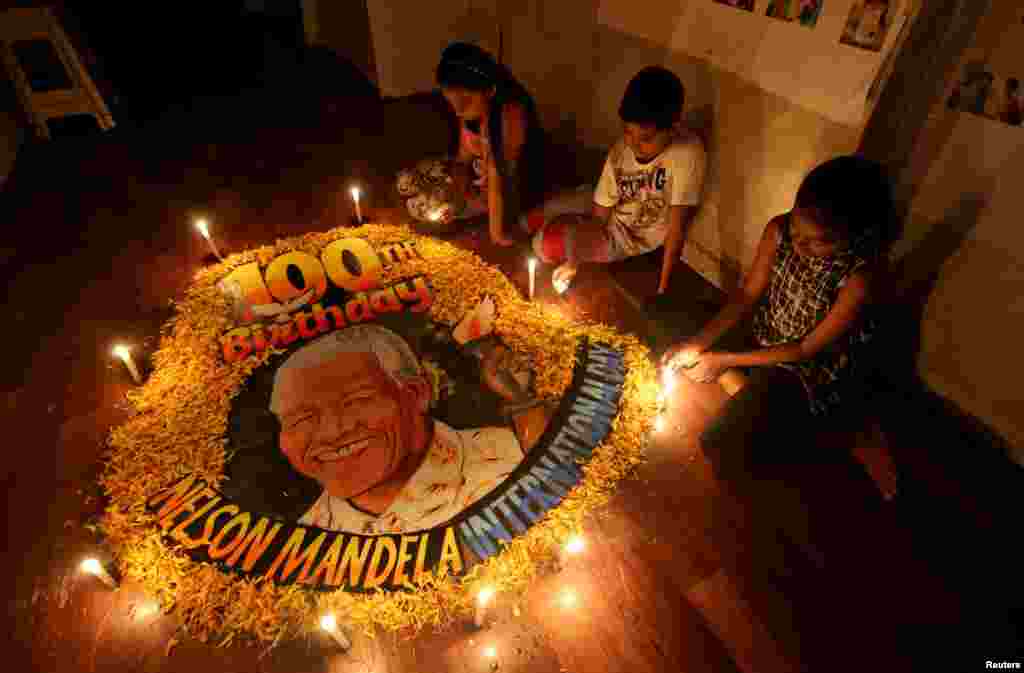 Children light candles beside a painting commemorating South African revolutionary Nelson Mandela's 100th birth anniversary at an art school in Mumbai, India.